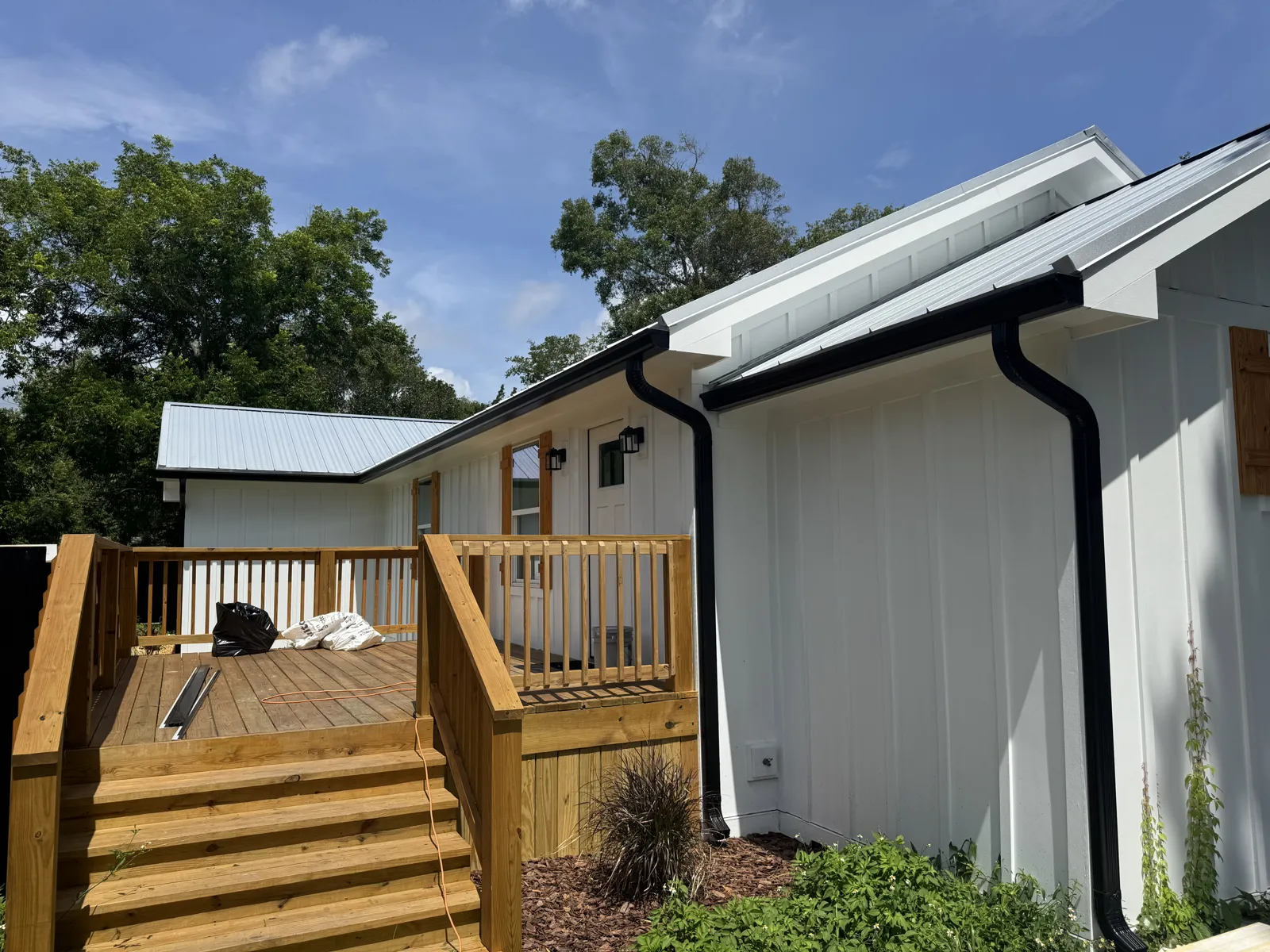 Black seamless gutters and downspouts installed by LePierre on a white board-and-batten home