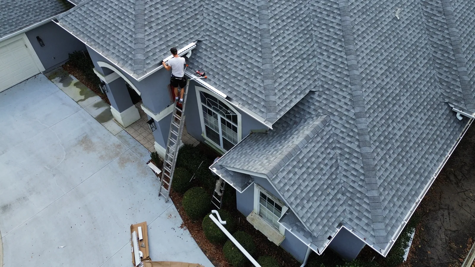 Aerial view of a LePierre technician installing gutters at the roofline