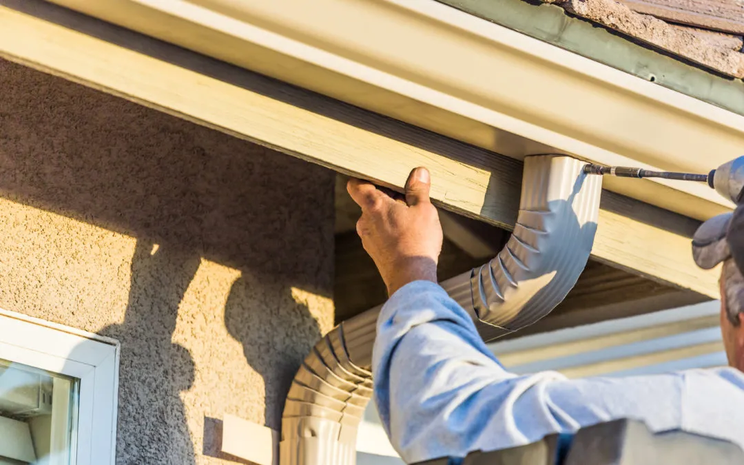 Installer attaching a downspout elbow under an eave